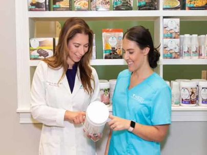 Female doctor looking at supplements with a woman in scrubs.