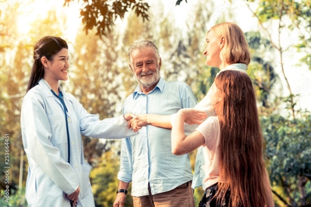 Smiling doctor greeting people in a park.