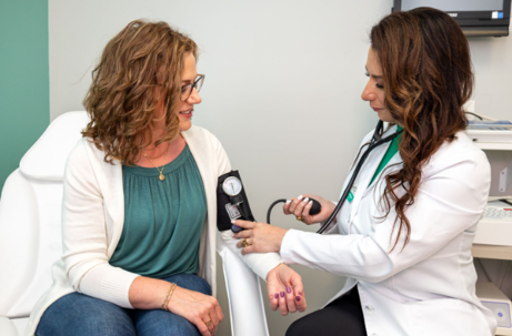 A healthcare provider in a white coat measures a patient's blood pressure with a cuff. | Medi-Weightloss