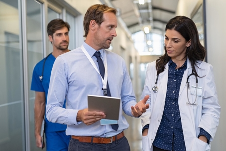 Male businessman holding a tablet and a female doctor. | Medi-Weightloss